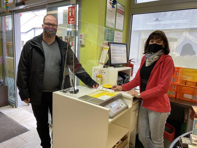 Bürgermeister Martin Almstädter holt das erste Paket bei Postpartnerin Irina Podac Acatrinei