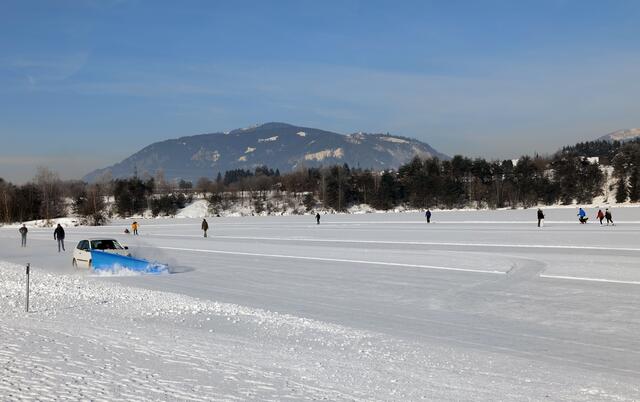 Das Bild zeigt den zugefrorenen Silbersee und Eisläuferinnen und Eisläufer.