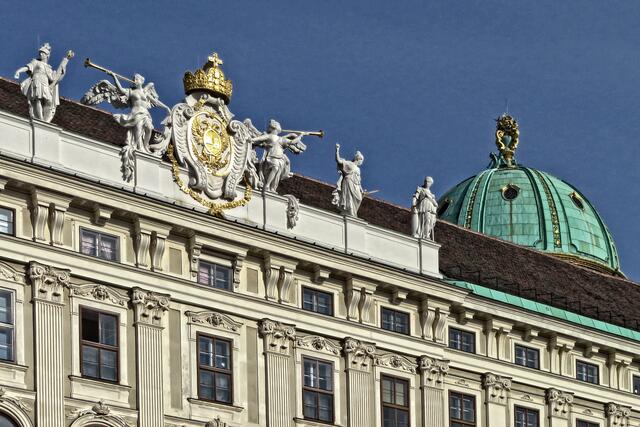 Über der Mauerkrone ist die sogenannte Michaelerkuppel, die den Michaelertrakt ziert, zu erkennen