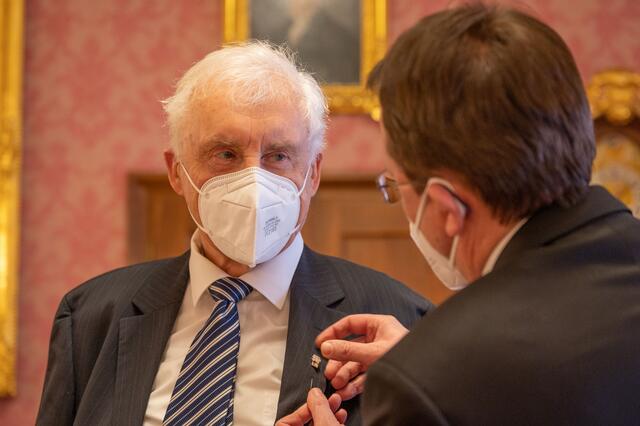 Bürgermeister Matthias Stadler steckt die Nadel mit dem Ehrenzeichen der Stadt St. Pölten an das Jackett von Manfred Deistler an.  | Foto: Arman Kalteis