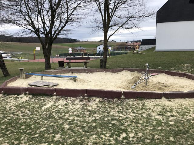 Sandkiste mit Bagger und Wasserlauf am Spielplatz in Phyra.