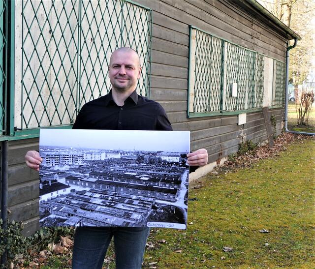 Thomas Rammerstorfer mit einem Bild des ehemaligen Flüchtlingslagers vor der letzten Baracke. | Foto: Grüne