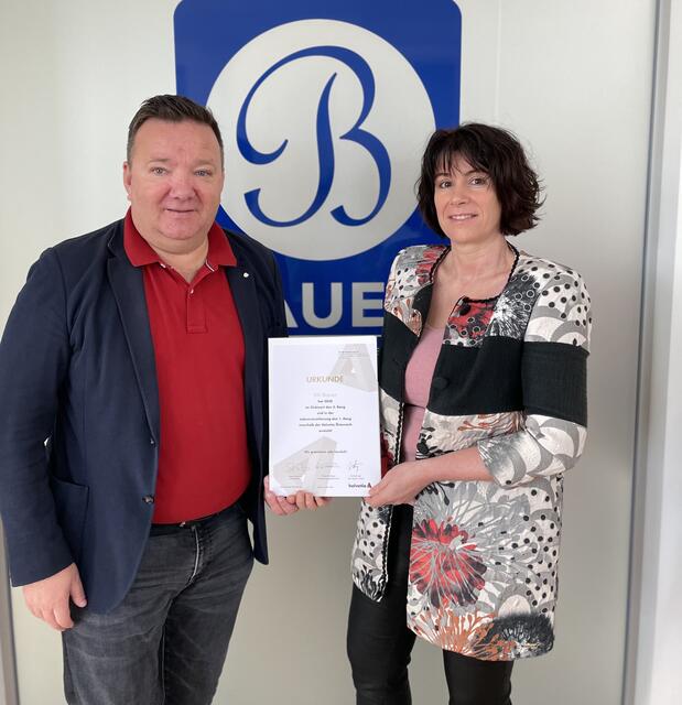 Erwin und Maria C. Bauer präsentieren die Urkunde der Helvetia Versicherung.