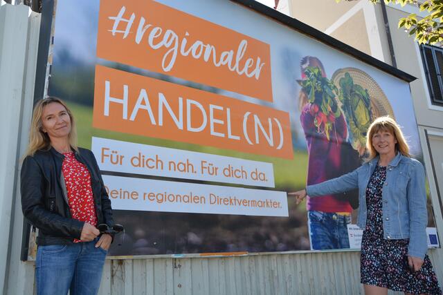 Gabi Jahn und Beatrix Übelacker von der LEADER Region Thermenland-Wechselland vor eines der insgesamt acht Plakate des Projekts "Handel im Wandel".