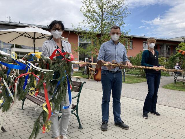 Alle drei Bäume wurden sehr klein gewählt, ja so richtige „Corona-Maibäume“ halt. 
Von li. n. re.: Beata Simko/Pflegedienstleiterin, Peter Loder- Taucher/Hausleiter und Bettina Gruber/Sekretariat.