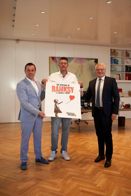 Tabakfabrik-Direktor Chris Müller (li.) mit Veranstalter Oliver Forster (Mitte) und Bürgermeister Klaus Luger geben die neue Ausstellung über Street-Artist "Banksy" in der Tabakfabrik bekannt. | Foto: Stadt Linz