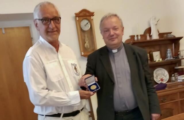 Stadtwache-Obmann Luigi Pisano bekommt von Stadtpfarrer Friedrich Weingartmann den Baustein in Gold überreicht.