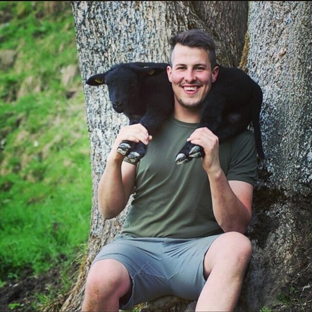 Michael Gassner freudestrahlend mit einem süßen Lämmchen auf seinen Schultern.