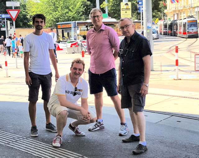 Christopher Hetfleisch-Knoll (Grüne), Harald Mader (ÖVP), Johannes Bachleitner (NEOS) und Andreas Schöll (ÖVP) weisen auf Schäden am tastbaren Leitsystem auf der Kennedybrücke hin.