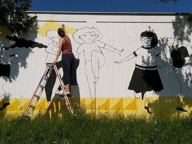 Illustratorin katuuschka arbeitet an der Außenmauer des St. Barbara Friedhofs.