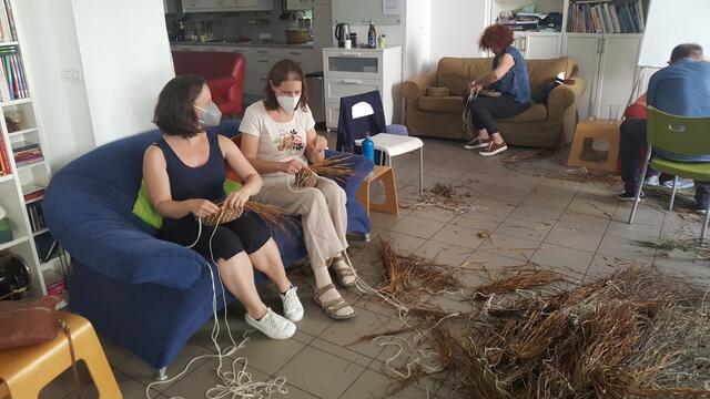 im hellen T-Shirt ist die Organisatorin Anita Zrounek beim Graskörbeflechten zu sehen