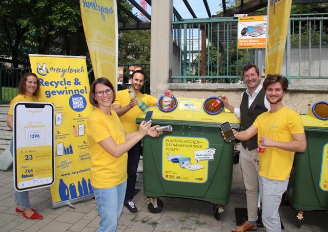 Das "RecycleMich-App"-Team zeigt an der Gelben Tonne wie es geht: Tonne und Barcode am Leergut mit dem Handy fotografieren und dann entsorgen!