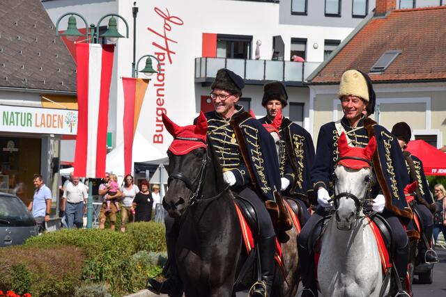 Die Kaiserhusaren traben als Teil des Umzuges auf ihren Pferden mit.