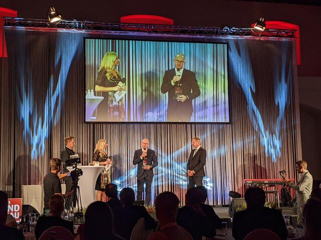 Der Sieger des Sonderpreises „Oberösterreicher von Herzen“, Bernd Lamprecht (Mi.), auf der Bühne mit Landeshauptmann Thomas Stelzer (r.), Bezirksrundschau Chefredakteur Thomas Winkler (l.) und Moderatorin Nina Kraft.