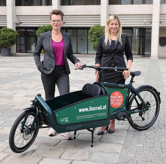 Stadträtin Eva Schobesberger (links) und Stadträtin Doris Lang-Mayerhofer freuen sich über das neue familienfreundliches E-Lastenrad der Marke Bullitt, das ab Anfang Oktober die Flotte ergänzt.  | Foto: Stadt Linz