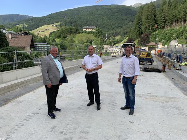 "Die Gemeinde erhält erstmalig eine wirklich Lkw-taugliche Zufahrt sowie einen neuen Gehsteig nach Matrei", so Bgm. Alexander Woertz zu den noch laufenden Arbeiten. Im Bild ist er mit seinem Mühlbachler Amtskollegen Alfons Rastner und LH-Stv. Josef Geisler auf der neuen Brücke beim Pfoner Eck zu sehen.