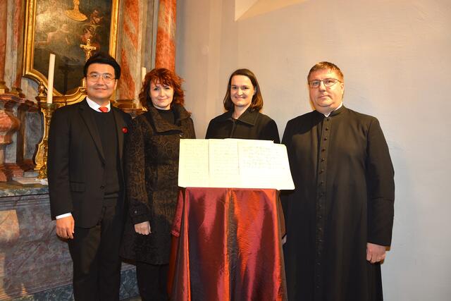 Chorleiter Suyoung Ham mit Bettina Eder und Sandra Brünner vom Gesangverein Burgau und Pfarrer Mathias Trawka vor den Noten des "Ave Maria" vom Burgauer Komponist Franz Frenz, die bei der Entrümpelung des Pfarrhofes gefunden worden waren.