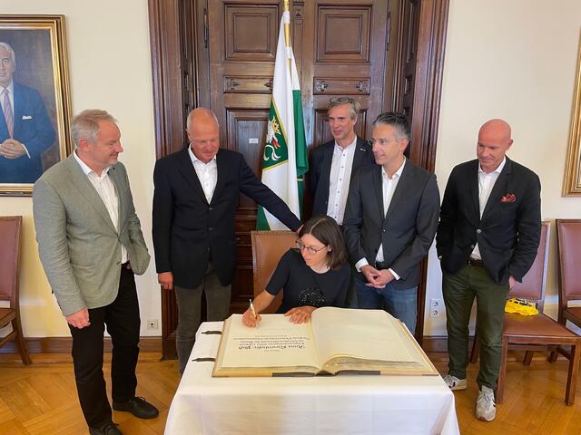 Eine Olympiasiegerin im Goldenen Buch der Stadt: Anna Kiesenhofer mit Thomas Rajakovics, Gerald Pototschnig, Klaus Kabasser, Kurt Hohensinner und GR Peter Stöckler (v.l.)