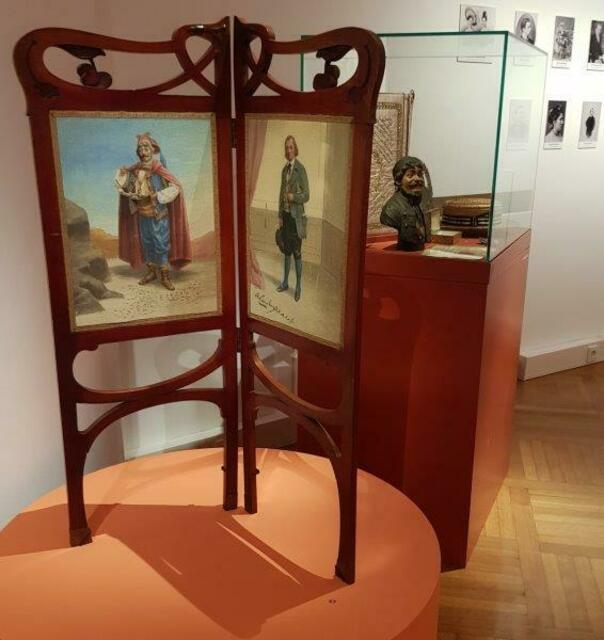 Girardi als Paravan-Dekoration, sein HUt daneben in der Vitrine
