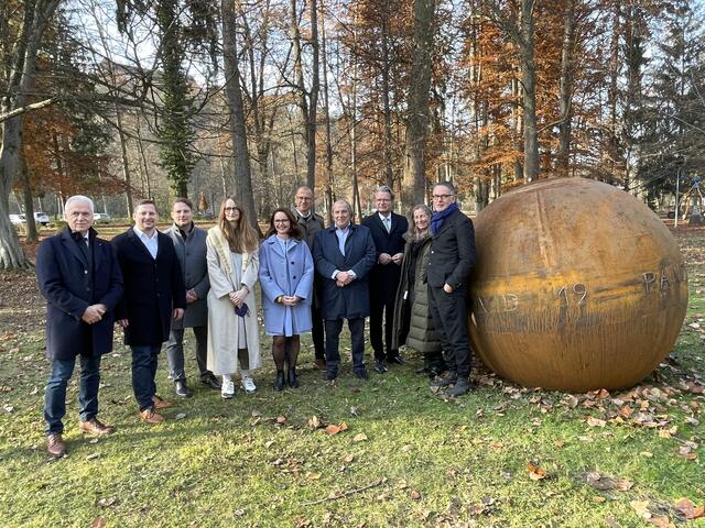 Bürgermeister Helmut Leitenberger, Ideengeber Jörg Schwaiger, Gerald Schwaiger, Henriette Gallus (stellvertretende Intendantin steirischer herbst und Jury-Mitglied), Alexia Getzinger (kaufmännische Geschäftsführerin UMJ), Wolfgang Muchitsch (wissenschaftlicher Geschäftsführer UMJ und Jury-Mitglied), Jury-Vorsitzender Ralph Schilcher, Kulturlandesrat Christopher Drexler, Elisabeth Fiedler (Leiterin Institut für Kunst im öffentlichen Raum und Jury-Mitglied) und Künstler Werner Reiterer (v.l.) mit dem Corona-Denkmal.
