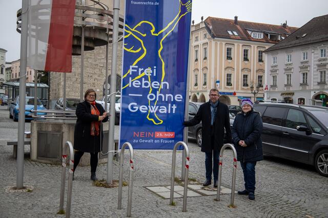 Christine Baumgartner Geschäftsführerin des Frauennetzwerks Linz-Land, Bürgermeister Christian Deleja-Hotko und Stadträtin Marieluise Metlagel hissen die "Gewaltschutzflagge" am Ennser Hauptplatz.