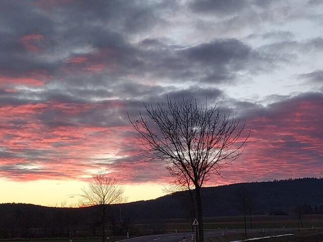 Die untergehende Sonne färbt die Wolken rot.