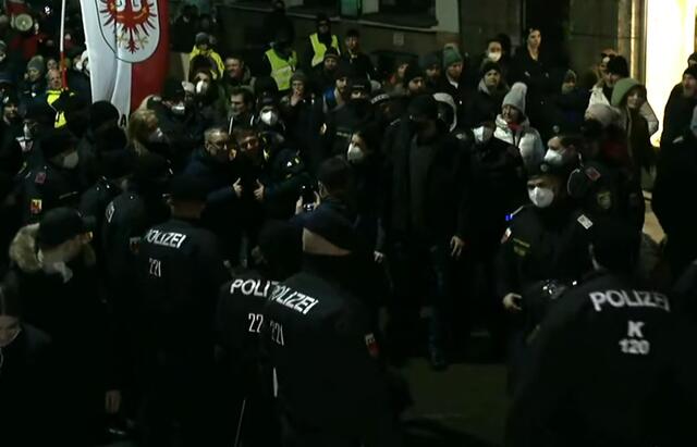Herbert Kickl beim Spaziergang umgeben von zahlreichen Polizisten.