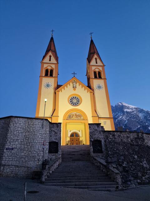 Vor dem Hintergrund des markanten Hausbergs Hohe Munde strahlt die Südfassade der monumentalen Pfarrkirche Peter und Paul jetzt im LED-Licht. | Foto: GWTelfs/Hirn