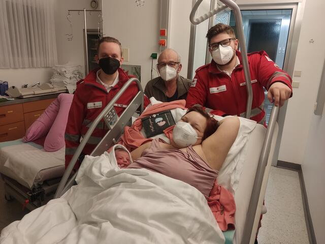 Die zweifache Mutter mit ihrer Laura-Aurelia in den Armen, hinter ihr stehend die Rettungsmannschaft und ihr Großvater. | Foto: RKNÖ/RK Atzenbrugg