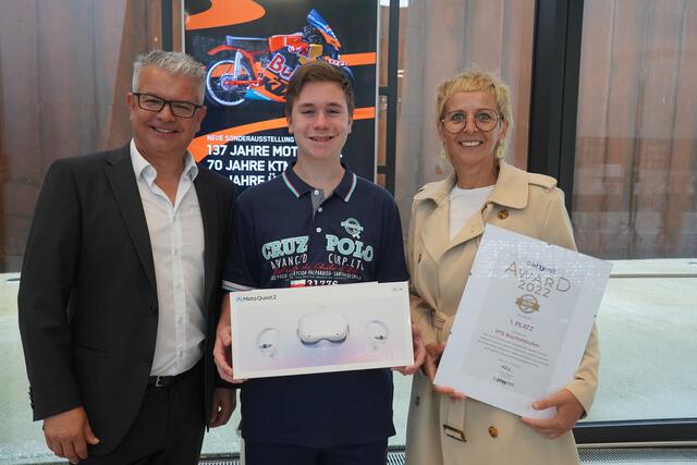 In der KTM-Motohall in Mattighofen beim Playmit-Award 2022. Von links: Michael Heppler, der Vertriebsleiter von Playmit, der Gewinner Wolfgang Riedel von der Polytechnischen Schule (PTS) Bischofshofen und die Direktorin der PTS Bischofshofen, Elisabeth Saller. | Foto: Emanuel Hasenauer