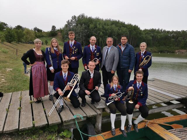 Dirigent, Komponist und Initiator Daniel Muck (Bildmitte) mit  Musikern und politischen Mandataren beim Abendkonzert am Fischerteich. 