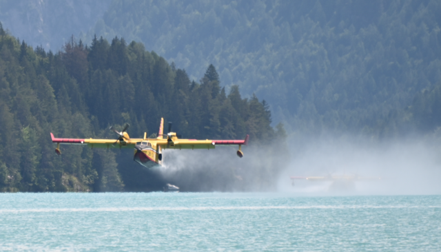 Ein Flieger hat bereits Wasser aufgenommen, hinten sieht man den zweiten Flieger, der noch Wasser aufnimmt.