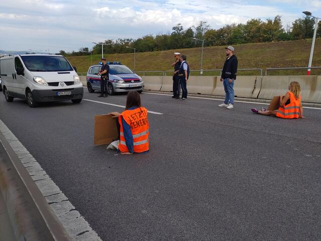 Zwei Personen haben sich mit den Händen an die Fahrbahn geklebt. | Foto: Letzte Generation AT