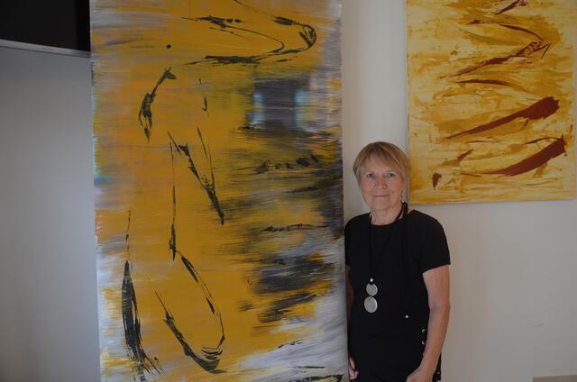 Dorly Vany zwischen ihren schwungvollen abstrakten Bildern