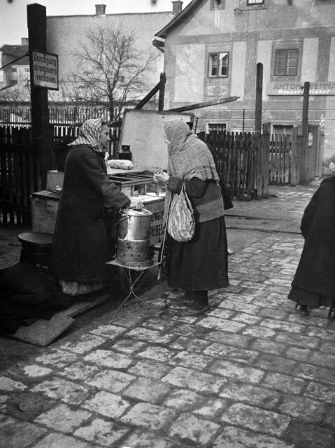 Damals um 1930: Würstelfrau in Urfahr
Kleine Essensstände wie diese Würstelfrau in Urfahr waren damals nicht aus dem Stadtbild wegzudenken. An belebten Standorten boten sie zu verhältnismäßig günstigen Preisen ihre Waren feil und stellten damit ein niederschwelliges Essensangebot für die Bevölkerung dar. Für ihre Betreiber war diese Form des Kleingewerbes wiederum oft die einzige Möglichkeit sich ihren Lebensunterhalt zu verdienen. | Foto: Archiv der Stadt Linz