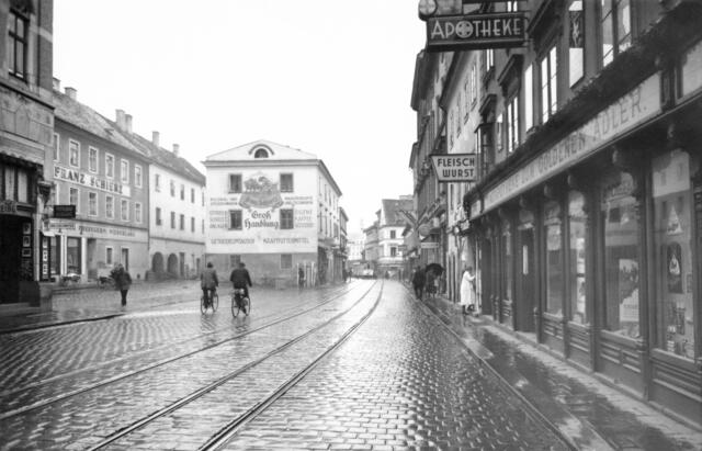 Damals 1939: Die Urfahrer Hauptstraße
Mit der 1872 fertiggestellten Eisenbrücke wurde die Urfahrer Hauptstraße zur wichtigsten Geschäftsstraße von Urfahr. Die Straßenbahn im Bildhintergrund befindet sich auf der Höhe der Kreuzung mit der Ottensheimer Straße. Die Kreuzung verschwand wenig später mit der Errichtung der Rampe der Nibelungenbrücke, durch die auch die linksseitige Häuserzeile an der Hauptstraße unter das Straßenniveau zu liegen kam. | Foto: Archiv der Stadt Linz