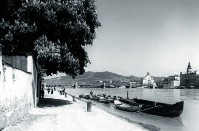 Damals um 1915: Die Donaulände in Urfahr
Die nach 1912 entstandene Aufnahme zeigt die obere Urfahrer Donaulände auf der Höhe der Schiffgasse. Sie wurde 1890 bis 1896 aufgeböscht und entwickelte sich zum beliebten Spazierweg. Für das Anlanden der Schiffe nahm die damalige Stadt Urfahr eine Haftgebühr für die eingerammten Uferblöcke ein. Im Hintergrund auf der Linzer Donauseite ist hinter der Eisenbrücke das ehemalige Hotel Weinzinger zu erkennen. | Foto: Archiv der Stadt Linz