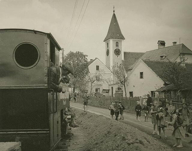 Damals 1938: Schulkinder in St. Peter
Im Jahr 1938 existierte der beliebte Ausflugsort der Linzer Bevölkerung noch. Er bestand aus einem Dorfzentrum mit Sicherheitswache, Kirche, Pfarrhof und der Schule. Die Kinder marschierten mit ihren Schulranzen gerade nach Hause. Die Lokomotive der Feldbahn, die für den geplanten Bau der Hermann-Göring-Werke angelegt wurde, läutete das Ende des Ortes St. Peter ein, der dem neuen Stahlwerk weichen musste. | Foto: Archiv der Stadt Linz