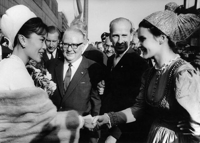 Damals 1964: Besuch des thailändischen Königspaars
Als „Asiens Jackie Kennedy“ gehörte die thailändische Königin Sirikit in den 1950ern- und 60ern zu den berühmtesten Frauen der Welt. Gemeinsam mit ihrem Ehemann, dem bekannten Langzeitkönig Bhumibol, unternahm sie in dieser Zeit ausgedehnte Reisen. Eine dieser Reisen führte die beiden 1964 nach Linz, wo die „bestgekleidete Frau der Erde“ beim Empfang Bekanntschaft mit oberösterreichischer Tracht machte. | Foto: Archiv der Stadt Linz
