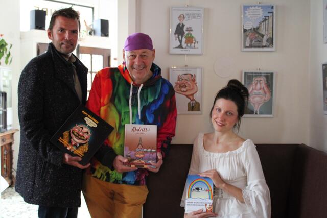 GR Christoph Kny, Künstler Reinhold Buchacher und Musikerin Yasmin Wischenbarth vor einer Karikatur von Bgm. Hans Stefan Hintner. 