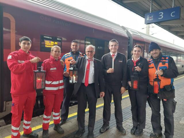Das Friedenslicht aus Bethlehem ist gut in Villach angekommen und wurde von Zugbegleiter Helfried Huber an Vertreter:innen des Roten Kreuzes und Mitarbeiter:innen der ÖBB übergeben. | Foto: ÖBB/RZP