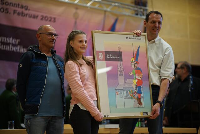 Die stolze Schöpferin des Plakats zur Buabefåsnåcht, Sarah Köhle (11) – neben ihr: Ihr Zeichenlehrer Lorenz Schimpfössl (l.) und Fåsnåcht-Schriftführer Nikolaus Larcher | Foto: Matt