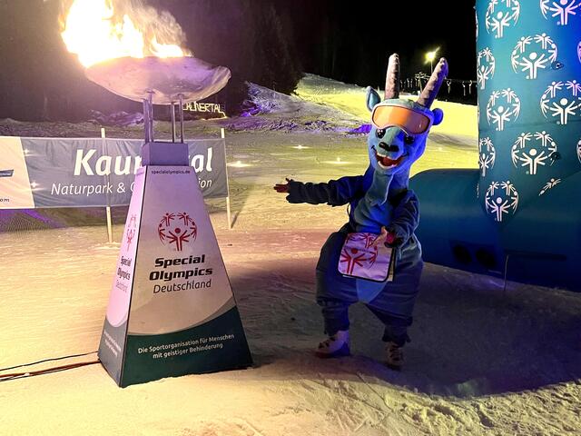 Kauni, das Maskottchen der Gletscherregion, mit specialolympischem Feuer. | Foto: © SOHE