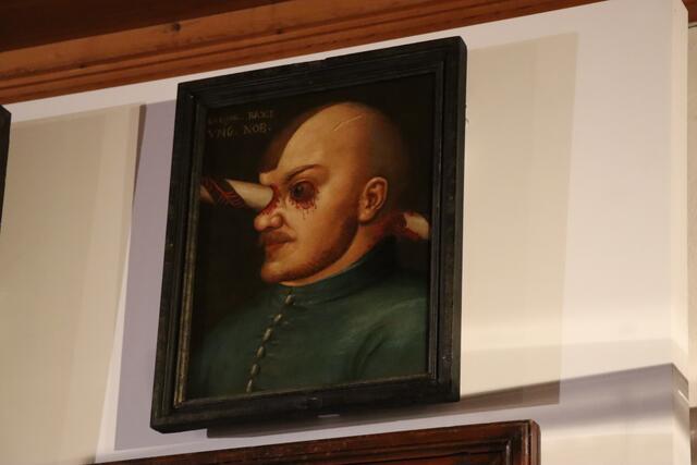 Das Gemälde zeigt Gregor Baci. Der ungarische Edelmann wurde bei einem Turnierunfall schwer verletzt. Er lebte mit einer Lanze im Schädel noch etliche Monate weiter. 