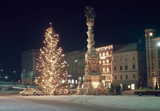 Außer dem stattlichen Christbaum unmittelbar neben der Dreifaltigkeitssäule ist die beleuchtete Weihnachtsdekoration am „Donau-Kaufhaus“ im Hintergrund gut zu erkennen. | Foto: Archiv der Stadt Linz