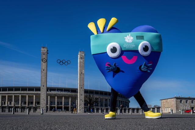 Das Maskottchen „Unity“ vorm Olympiastadion und vor dem Brandenburger Tor. | Foto: ©Berlin 2023