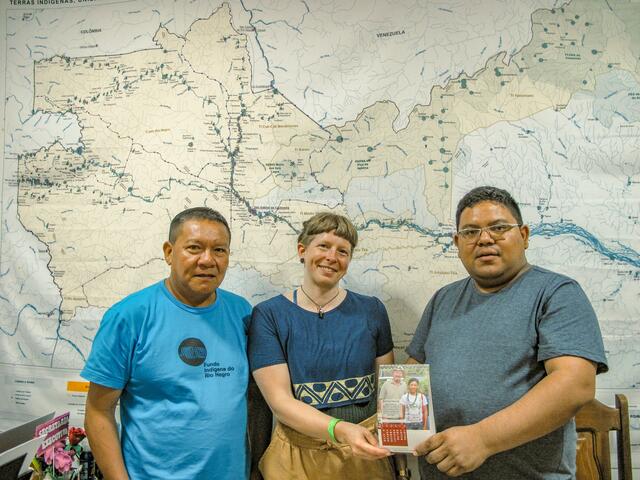 Rio Negro-Koordinatorin Kerstin Plaß mit den Partnern der FOIRN vor einer Karte des geschützten Gebiets. In ihren Händen halten sie ein Bild von Klimabündnis-Mitarbeiter Johann Kandler, welcher die Partnerschaft in den 1990ern aufbaute. | Foto: Klimabündnis Österreich