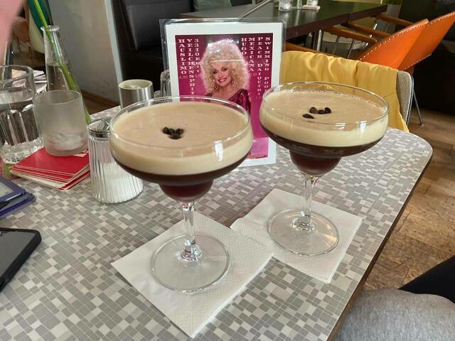 Dolly Parton in pinkem Glitzerkleid strahlt hinter zwei Espresso Martinis hervor. | Foto: Hacienda Ephemer