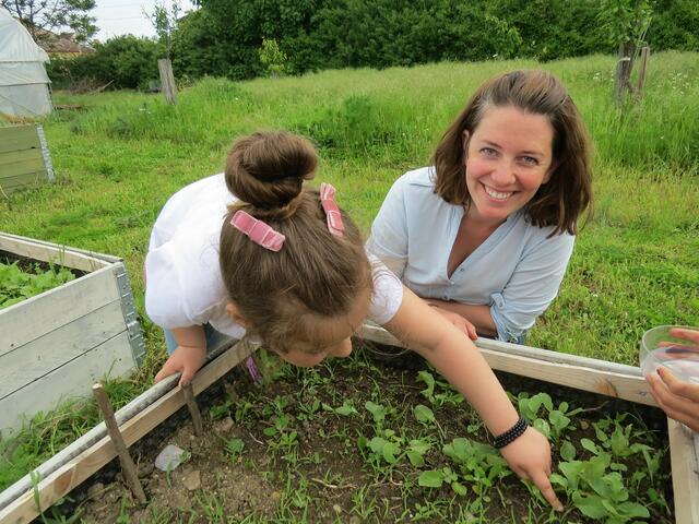 Eliona zeigt Marina Loibl ihre selbst gezogenen Radieschen.