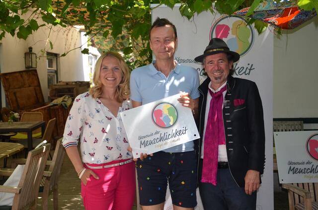 Erich Lux nahm die Logotafel von "Ökonomie der Menschlichkeit" entgegen, im Bild mit Moderatorin Birgit Perl und Georg Dygruber. | Foto: privat